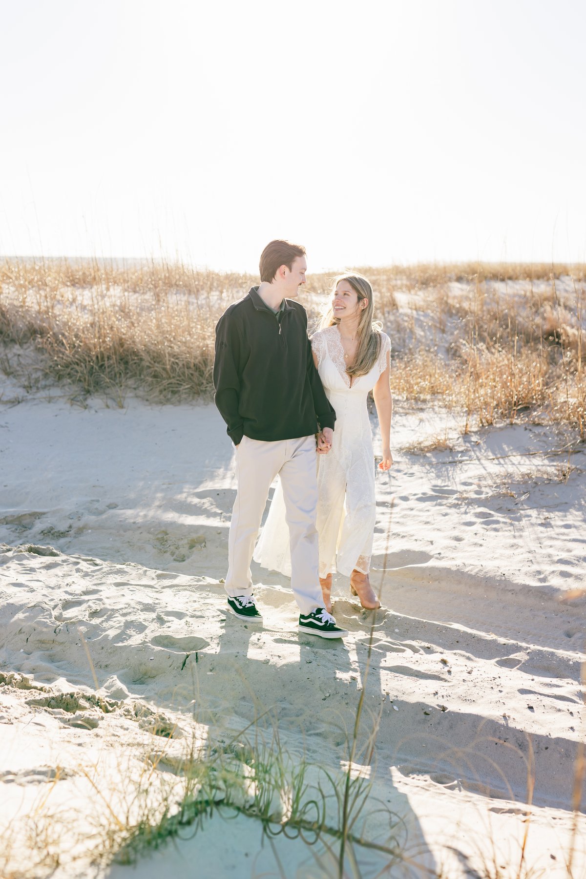 Catherine and Noah walking hand in hand on the beach at Pine Knoll Shores